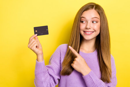 Photo of funny pretty lady stylish knitted jumper hand present bank card ebank emoney empty space isolated on yellow color backgroundの写真素材