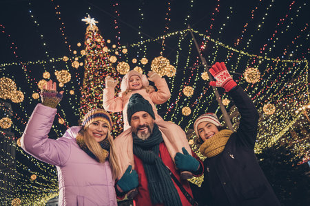 Photo of cheerful school children husband wife cuddling walking x-mas park waving arms riding...