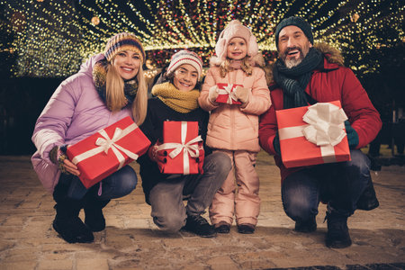Photo of pretty husband wife school children walking xmas park holding presents outdoors city fair