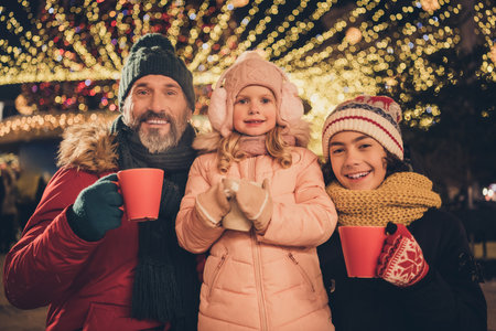 Photo of cute pretty young husband school girl boy drinking xmas beverages outdoors city fairの写真素材