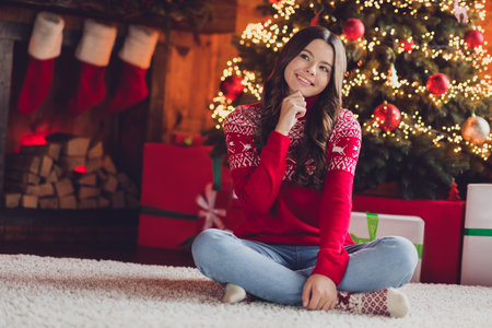 Photo of lovely tender sweet lady teen sit fluffy carpet curious look window waiting santa claus gifts enjoy evening indoors room houseの写真素材
