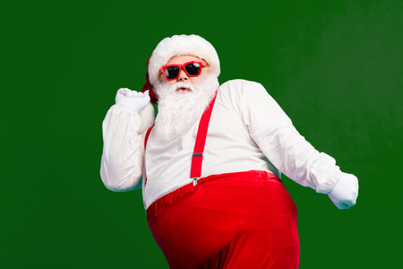 Photo of funky cool santa claus dance x-mas christmas newyear jolly discotheque wear headwear suspenders overall sunglass isolated over blue color backgroundの写真素材