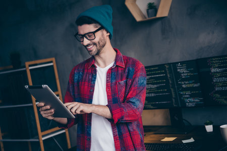 Photo of smiling cheerful programmer wear spectacles creating ebank application ebook modern device indoors workplace workshop homeの写真素材