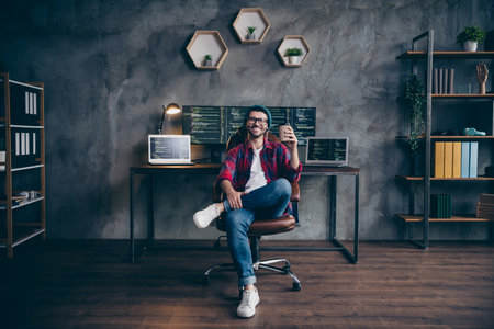 Photo of cheerful positive programmer wear spectacles enjoying tasty beverage indoors workplace...