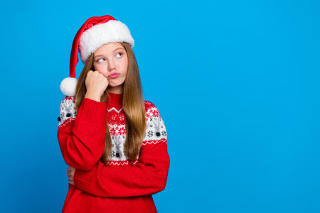Portrait of sad unhappy girl with blond hair wear red sweater hand on cheekbone look empty space isolated on blue color backgroundの写真素材
