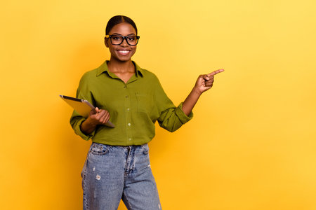 Portrait of attractive cheerful girl using gadget app 5g showing copy space isolated over bright yellow color backgroundの写真素材
