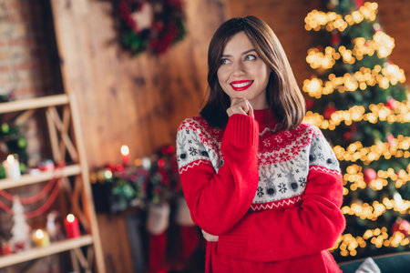 Photo portrait of charming smiling woman touch chin look mockup minded want wear old fashioned ugly sweater dreaming plans xmas tradition indoorsの写真素材