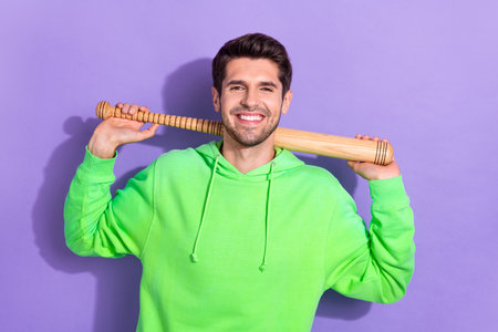 Portrait of young brunet hair man hold baseball bat professional vandal confident person wear green...