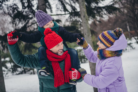 Portrait of three peaceful overjoyed people piggyback little boy have good mood free time walk...
