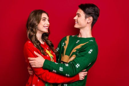 Profile portrait of two cheerful lovely partners cuddle look each other toothy smile isolated on red color backgroundの写真素材