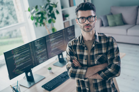 Photo of serious confident programmer wear spectacles arms folded indoors workplace workshop homeの写真素材