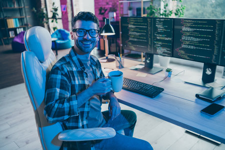 Photo of happy smiling guy wear glasses writing having working pause enjoying tea indoors workstation workshop homeの写真素材