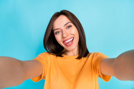 Portrait of cheerful positive person take selfie tongue lick teeth beaming smile isolated on blue color backgroundの写真素材