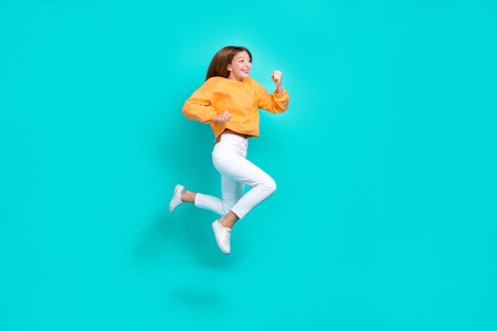 Full length photo of cheerful hurrying school girl dressed orange hoodie jumping high running fast...
