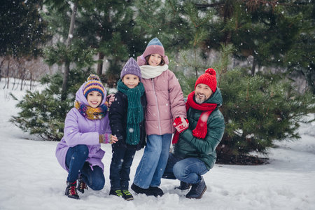 Photo of good mood funny husband wife small kid wear windbreaker enjoying snowy weather together outside urban city parkの写真素材