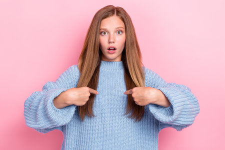 Photo of speechless funny excited teenager schoolgirl wear blue jumper fingers point herself speechless blame isolated on pink color backgroundの写真素材