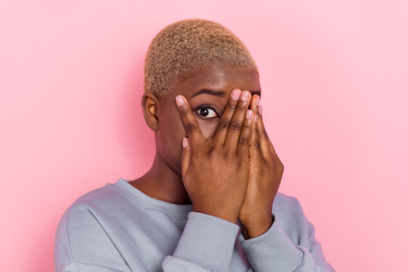 Portrait of young lady arms palms cover face one eye interested peeking isolated on pink color backgroundの写真素材