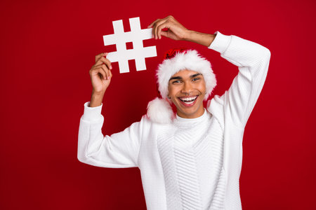 Photo of cheerful funky person toothy smile hands hold paper hashtag card isolated on red color...