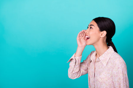 Profile photo of cheerful funky girl hand near mouth say tell look empty space isolated on teal color backgroundの写真素材