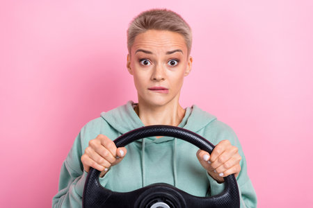 Photo portrait of pretty young girl nervous bite lips hold steering wheel dressed stylish khaki clothes isolated on pink color backgroundの写真素材