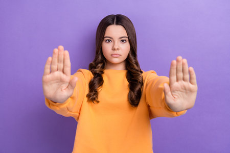 Portrait of serious concentrated girl hands palms demonstrate stop symbol isolated on purple color...