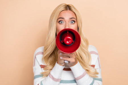 Closeup photo of crazy screaming loud information woman megaphone attention information protest activist isolated on beige color backgroundの写真素材