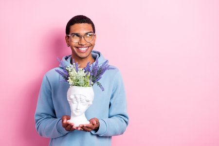 Photo of handsome attractive positive man designer hold statue flower houseplant pot dreamy look empty space idea isolated on pink color backgroundの写真素材