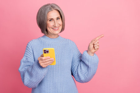 Photo of pensioner funny smiling positive grey hair woman wear blue jumper hold phone direct finger...
