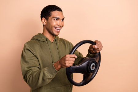 Photo of cheerful focused man wear khaki clothes look empty space enjoy first trip own car isolated on beige color backgroundの写真素材