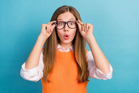 Photo of impressed crazy girl pouted lips arms touch eyeglasses isolated on blue color backgroundの写真素材