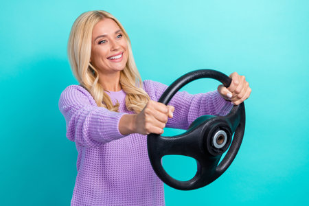 Profile photo of positive pretty lady arms hold wheel toothy smile look empty space isolated on aquamarine color backgroundの写真素材