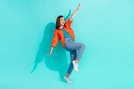 Full length photo of sweet pretty lady wear orange shirt having fun dancing isolated teal color backgroundの写真素材