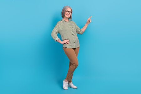 Full body photo of attractive business assistant senior smart casual clothes direct finger empty space vacancy isolated on blue color backgroundの写真素材