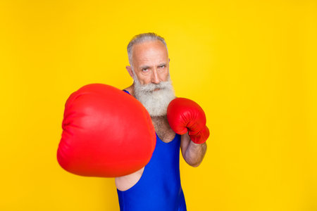Photo of focused concentrated person wear boxing gloves punch isolated on yellow color background