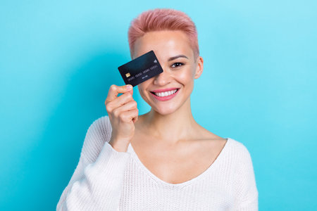 Photo of glad cheerful lovely lady wear stylish clothes hold plastic card recommend easy shopping isolated on blue color backgroundの写真素材