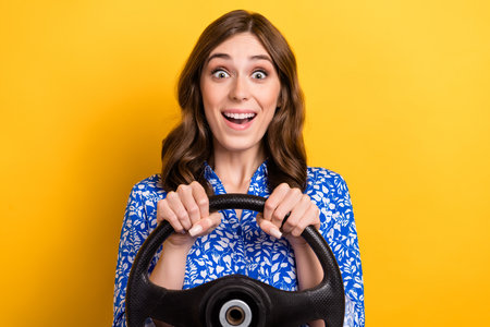 Photo of funny impressed lady wear print shirt smiling driving automobile isolated yellow color...