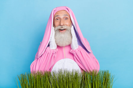 Portrait of impressed aged man hands touch cheeks toothy smile isolated on blue color background