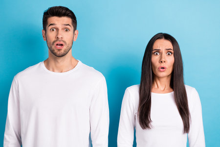 Photo portrait of attractive young male female astonished frightened reaction dressed stylish white look isolated on blue color backgroundの写真素材