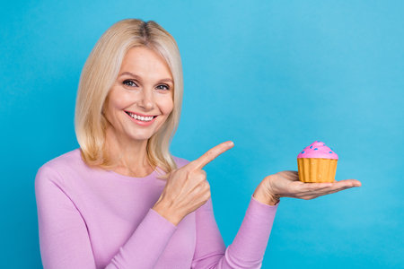 Photo of gorgeous glad stylish lady palm hold cake recommend taste fresh delicious bun empty space isolated on blue color backgroundの写真素材
