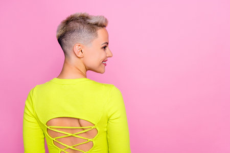 Rear behind portrait of gorgeous satisfied person beaming smile look empty space isolated on pink color backgroundの写真素材