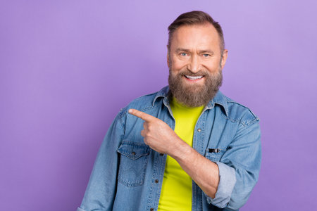 Portrait of positive friendly person beaming smile direct finger empty space isolated on purple color backgroundの写真素材