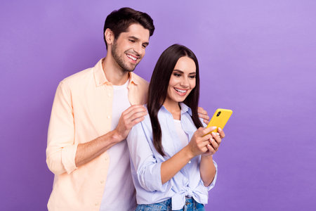 Photo of positive students people together choosing online delivery tasty food free service website smartphone isolated on violet color backgroundの写真素材