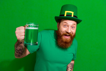 Photo of good moob guy dressed t-shirt cap rising ale beer glass celebrating clover day isolated...