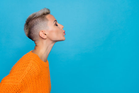 Photo of pretty flirty woman dressed knitted pullover closed eyes sending kiss empty space isolated blue color backgroundの写真素材