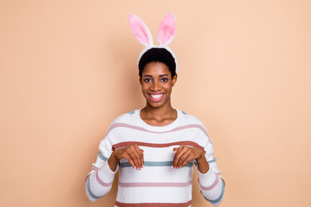 Photo of tricky fooling unisex person wear sweater rabbit headband showing arms bunny isolated beige...