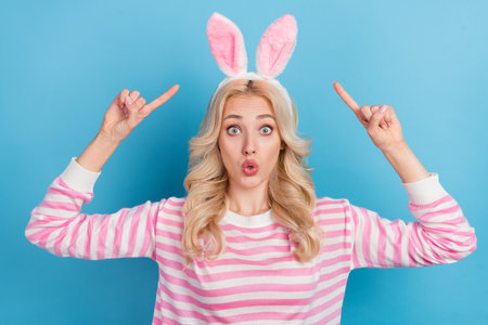 Photo of funny impressed lady dressed pink pullover pointing rabbit headband isolated blue color backgroundの写真素材