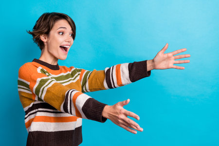 Photo of impressed funny lady wear striped sweater holding arms empty space isolated blue color backgroundの写真素材