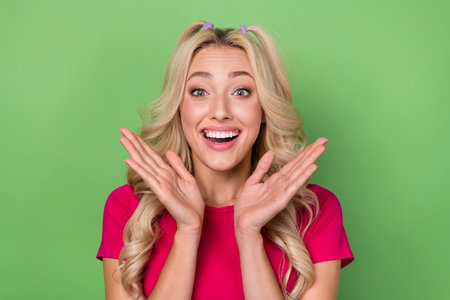 Photo portrait of young gorgeous pretty lady curly blonde hair hands cheeks unexpected good news proposition isolated on green color backgroundの写真素材
