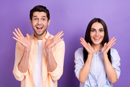 Photo of young couple students friends family brother sister siblings astonished cheap proposition unisex clothes isolated on violet color backgroundの写真素材