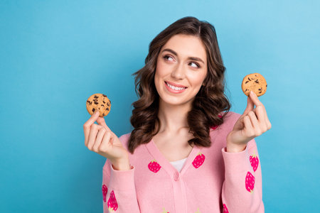 Photo of charming dreamy lady dressed pink cardigan rising gingerbread looking emtpy space isolated blue color backgroundの写真素材